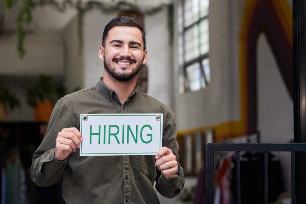 Portrait, man and we are hiring opportunity sign with recruiting, happy and smile from business own